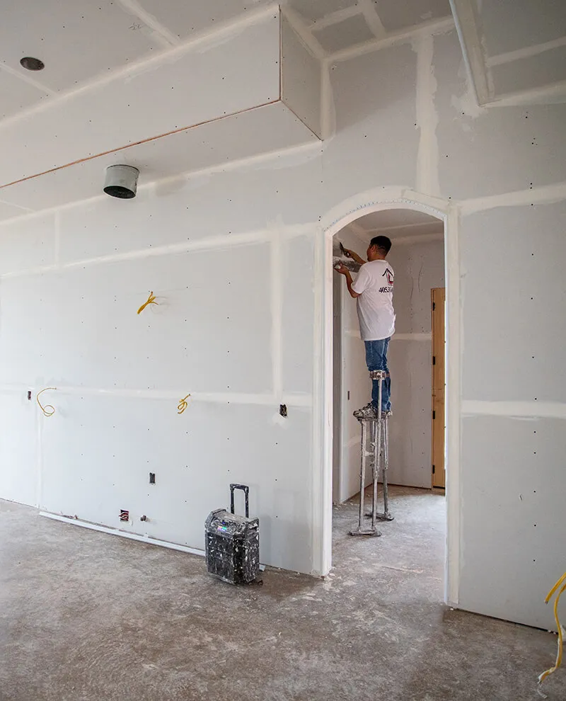 Quality Work Worker on stilts taping drywall